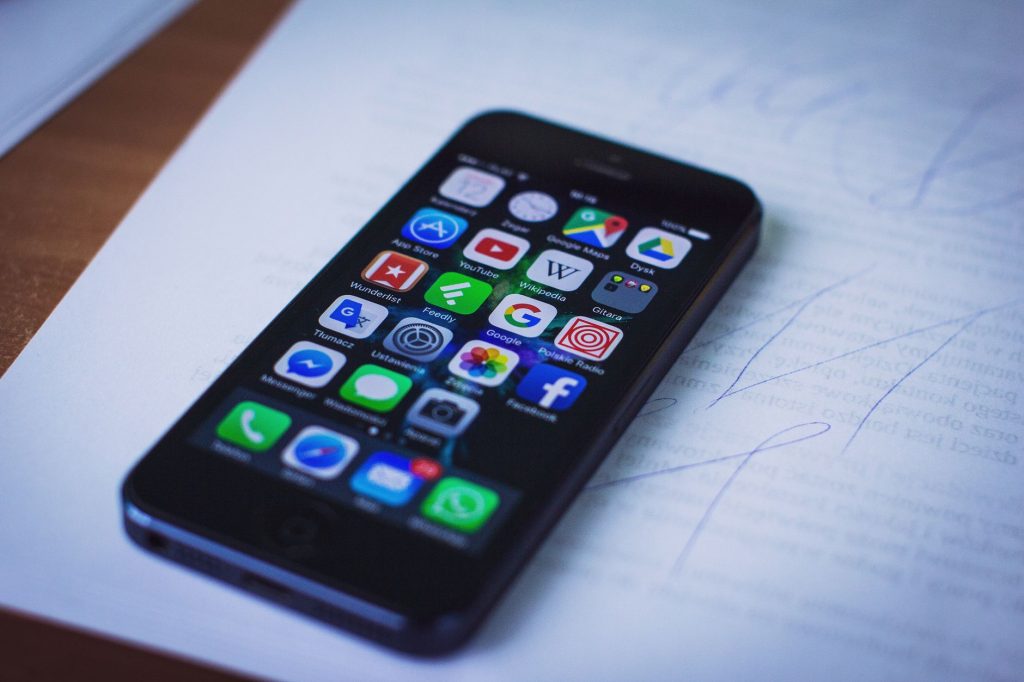 Modern smartphone displaying various apps resting on documents indoors. — A brief about legacy application modernization stra