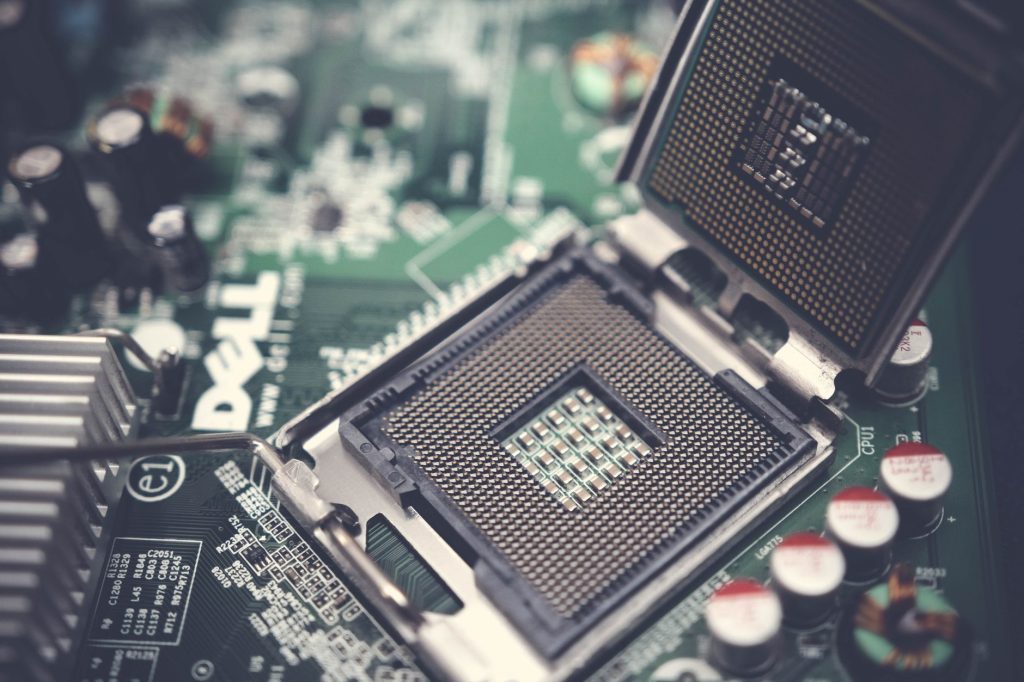 Detailed close-up shot of a computer motherboard featuring an open CPU socket and electronic components. — A Brief History of