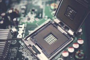 Detailed close-up shot of a computer motherboard featuring an open CPU socket and electronic components. — A Brief History of
