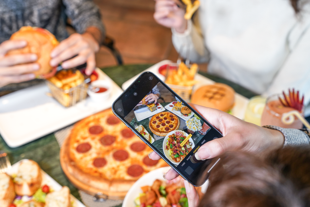 A vibrant scene with pizza, burgers, and fries being enjoyed and photographed by a group of friends. — Essential Aspects of a