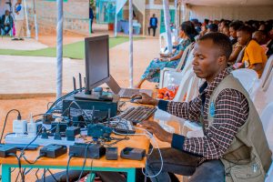 Technician managing electrical and computer setup at an outdoor event with attentive audience. — Find 4 Useful Tips to Upgrad