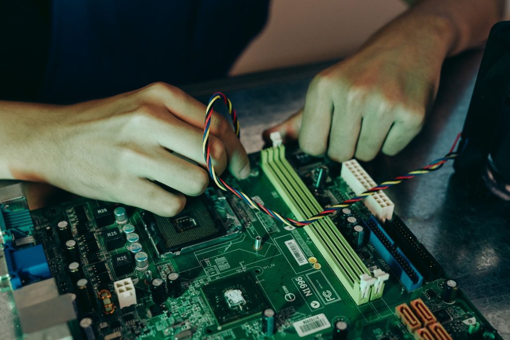 Person assembling computer motherboard with colorful wires, showcasing technology and engineering. — Find Out What You Requir