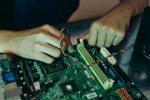 Person assembling computer motherboard with colorful wires, showcasing technology and engineering. — Find Out What You Requir