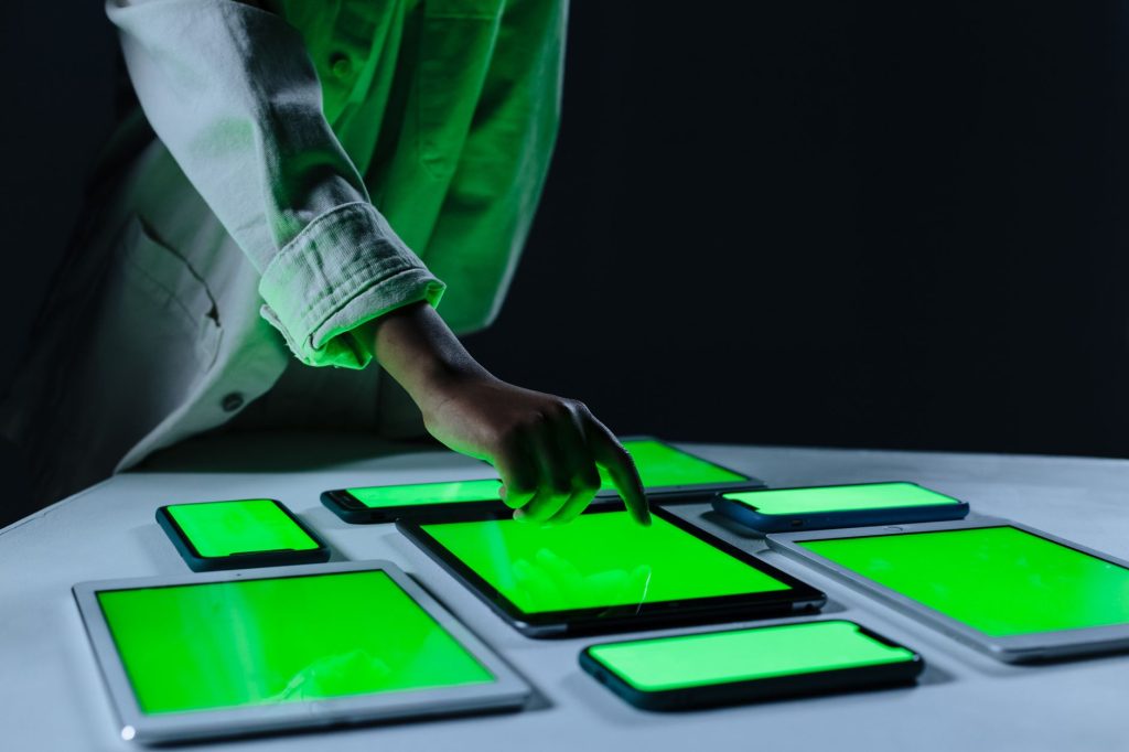 Hand interacting with multiple digital tablets on a green screen setup indoors. — How Does Legacy Code Conversion Work? Tip A