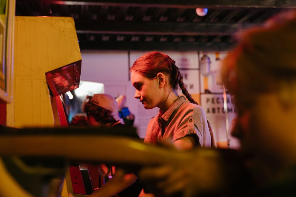 Teens playing at a vintage arcade with colorful lighting creating a nostalgic atmosphere. — How To Play Xgxbet - The Most Pop