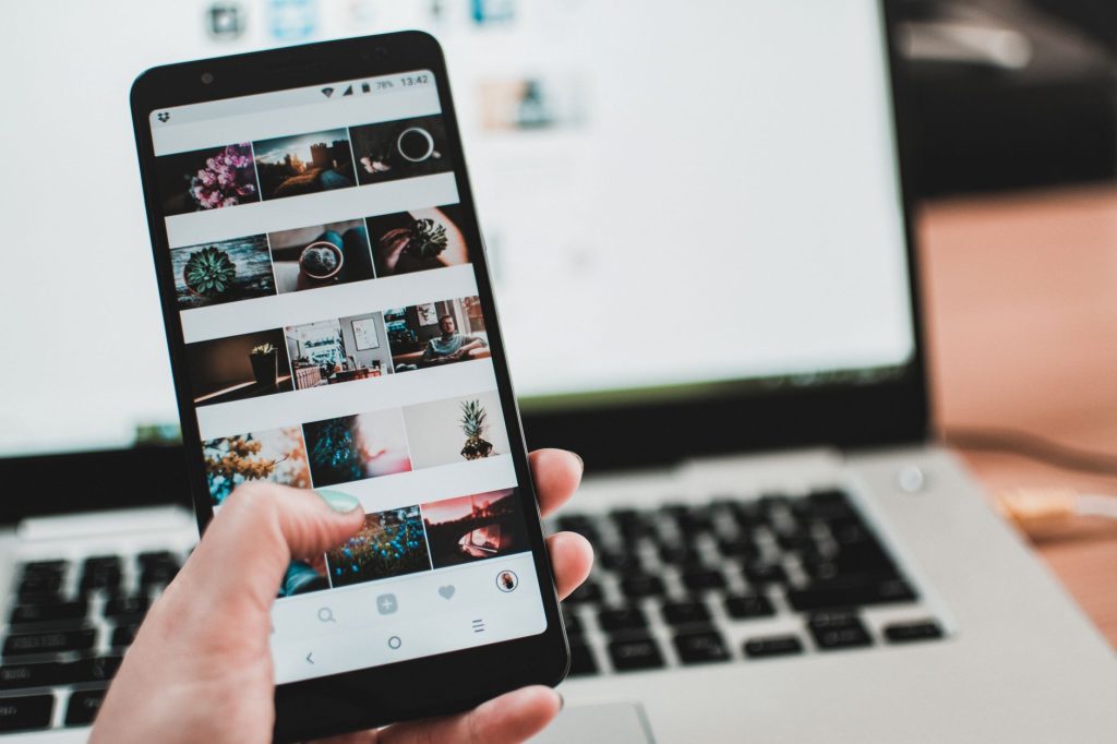 A person uses a smartphone to browse social media in front of a laptop, emphasizing modern technology and lifestyle. — How yo