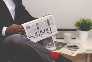 Businessman reading a financial newspaper at a desk, highlighting finance and commerce theme. — Influence Marketing Agencies: