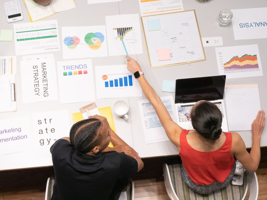 Colleagues collaborating on marketing strategy with documents and graphs in a modern office setting. — Just How Much to cover