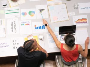 Colleagues collaborating on marketing strategy with documents and graphs in a modern office setting. — Just How Much to cover