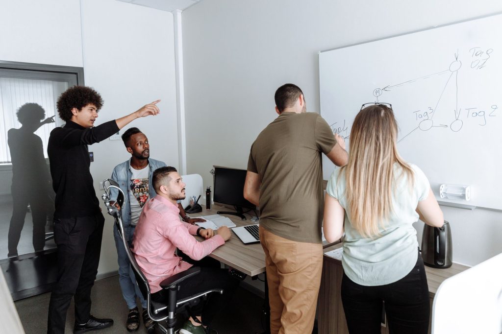A diverse group of young professionals brainstorming together in a modern office setting. — Outsourced Versus Internally Sear