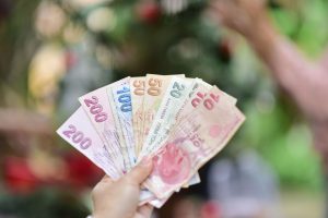 A hand holding multiple Turkish Lira banknotes in an outdoor setting, showcasing various denominations. — Part-Time Jobs For