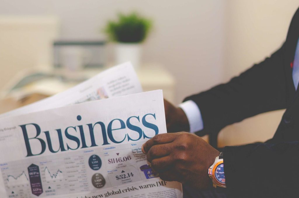Close-up of a businessman reading a newspaper indoors, focusing on business headlines. — Pokemon Shows in North Carolina: An