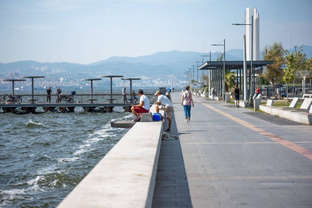 Serene seaside promenade with people fishing and strolling by the pier, set against coastal views. — Relaxing Sensual Nuru Ma