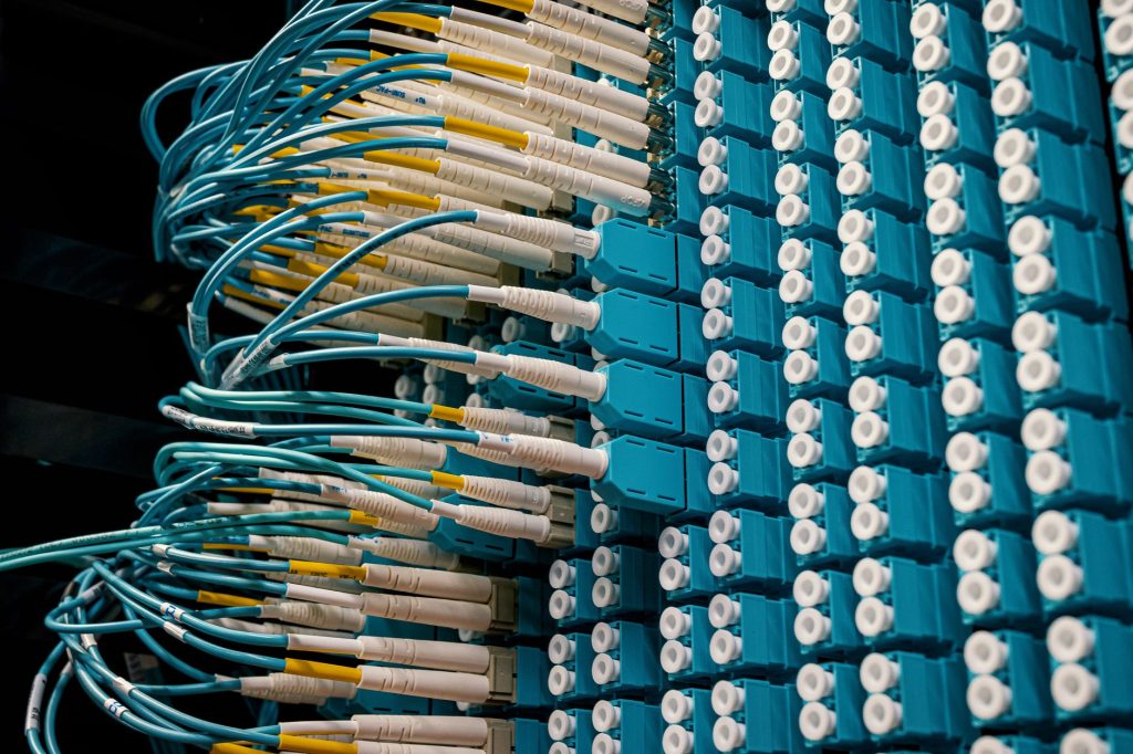 Detailed view of fiber optic patch cables connecting to a blue patch panel in a data center. — Review Fax-To-Email Services -