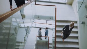 Aerial view of professionals conversing in a glass staircase in a modern office. — Safely Grow Your Audience by Buying YouTub