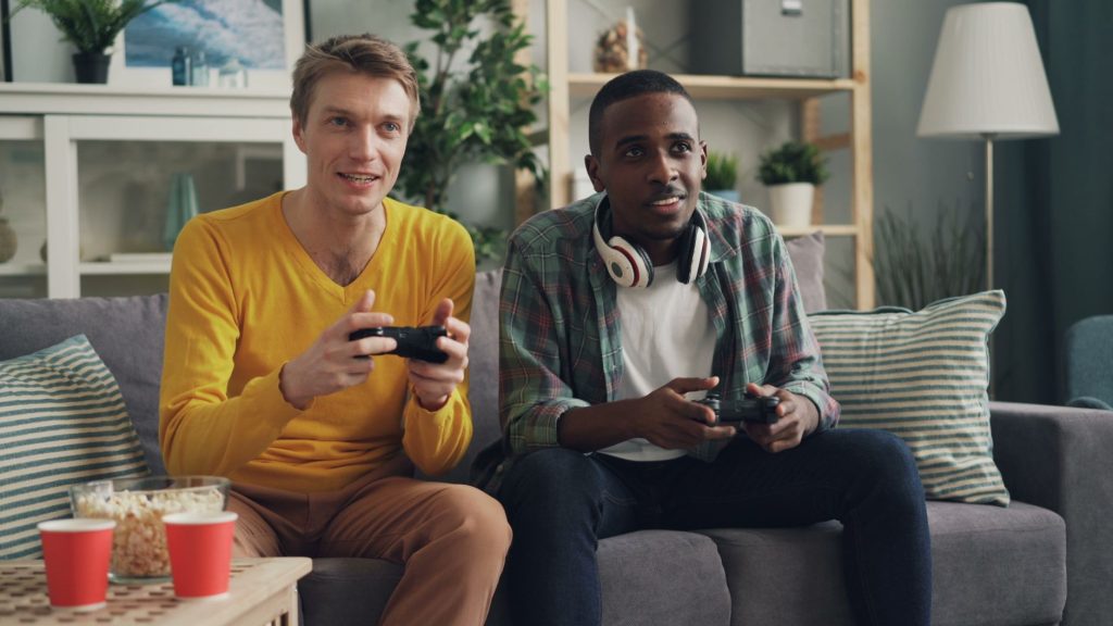 Two men sitting on a couch playing video games, focused and engaged. — Win Big With Multipliers and Free Spins