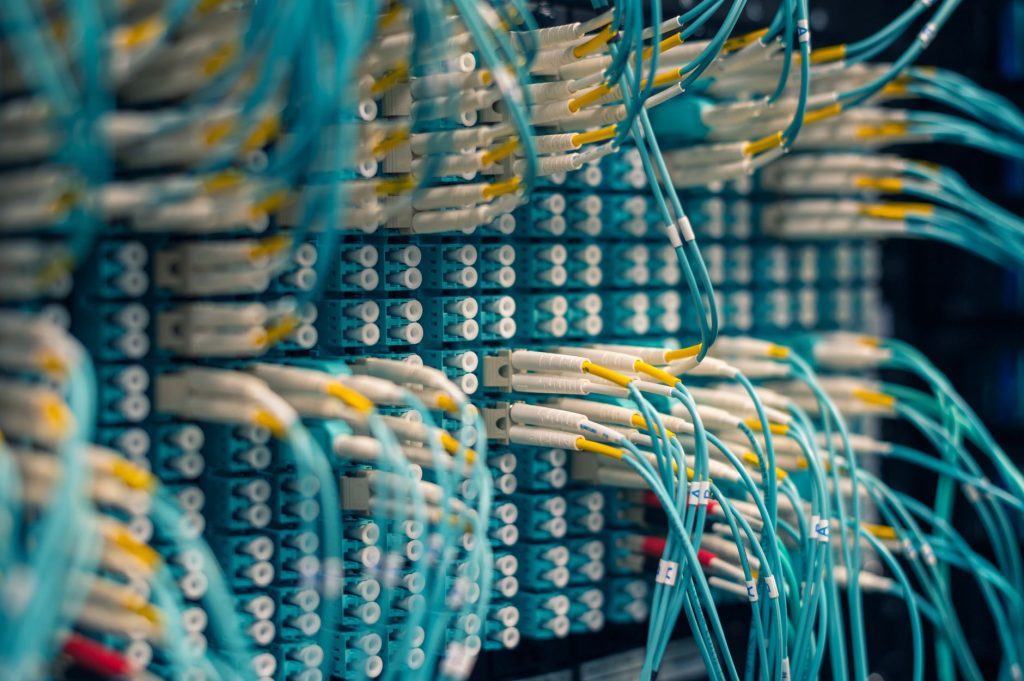 Closeup of rows of tiny round white electrical connectors and long thin blue wires in data center — The main feature of the T