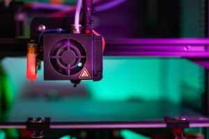 Vibrant close-up of a 3D printer component in action with colorful lighting creating a modern industrial vibe. — The Outcome