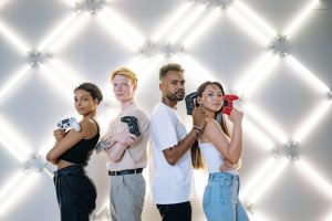 Four diverse friends posing confidently with game controllers against a modern LED backdrop. — Unlimited Lottery Betting with