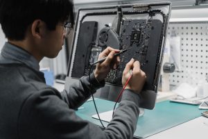 A technician works on a computer motherboard using tools at a workspace, focusing on electronics repair. — User Activity Moni